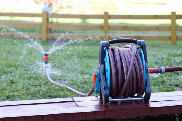 En Slangvinda används för att vattna en trädgård.